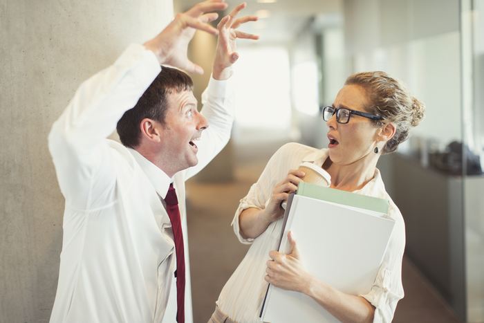 Businessman making snarling gesture at terrified businesswoman / Sources Getty Images