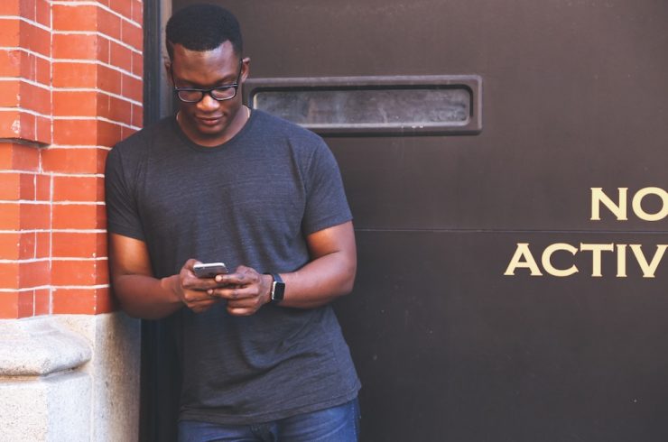 jeune homme consultant son smartphone dans le rue, sa data étant analysée par des spécialistes du sport business